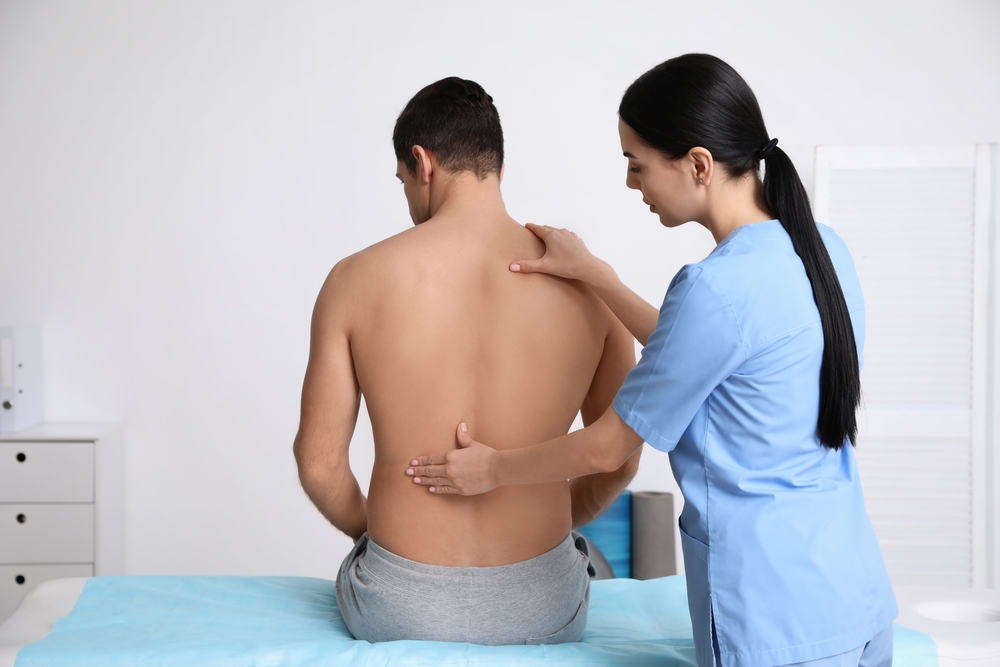 Orthopedist,Examining,Man's,Back,In,Clinic